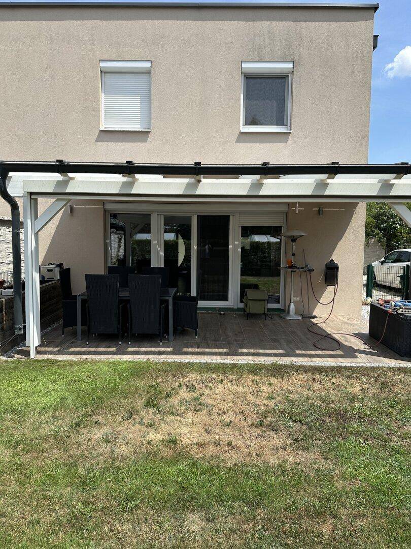 Überdachte Terrasse mit Gartenmöbeln und Blick auf den Rasen, perfekt für entspannte Stunden im Freien.