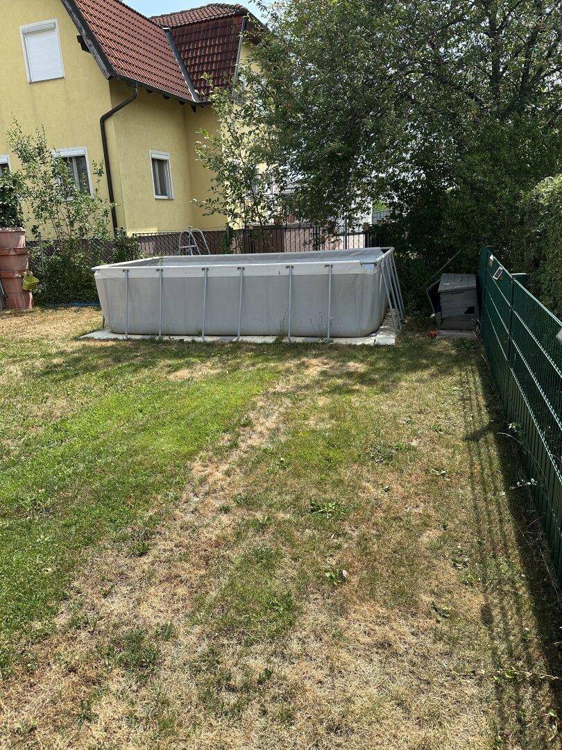 Gartenbereich mit einem rechteckigen Aufstellpool und Rasenfläche, ideal für sommerliche Erfrischung.