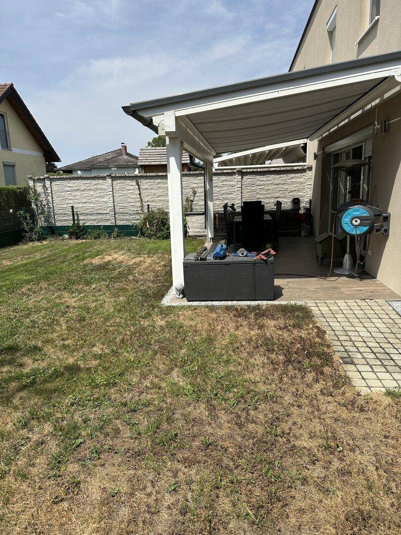 Überdachte Terrasse mit Gartenmöbeln und Blick auf den Rasen, perfekt für entspannte Stunden im Freien.