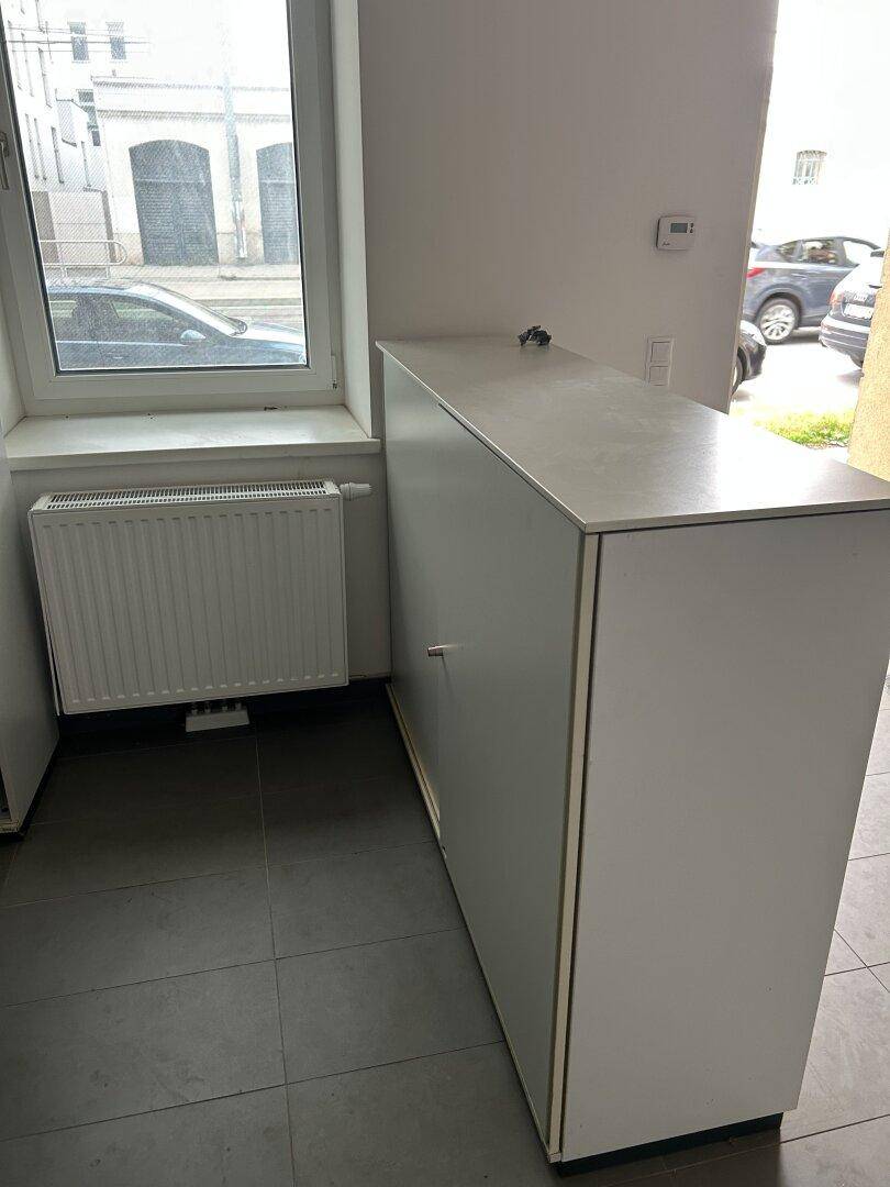 Fensterbereich mit einem schmalen Schrank und Heizkörper, der den Raum mit Wärme versorgt.