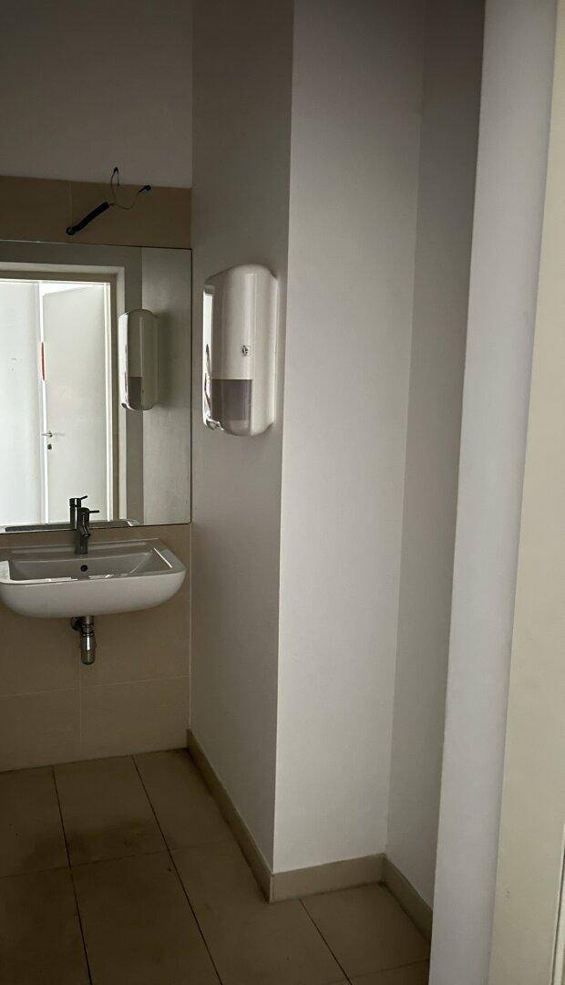 Badezimmer mit Waschbecken, großem Spiegel und Seifenspender, sauber und gepflegt.