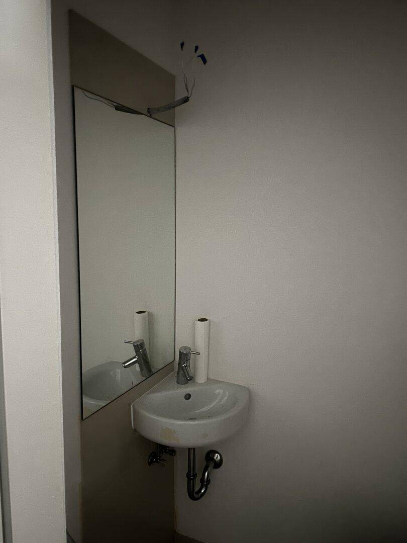 Kleines Badezimmer mit Waschbecken und Spiegel, funktional und einfach gestaltet.