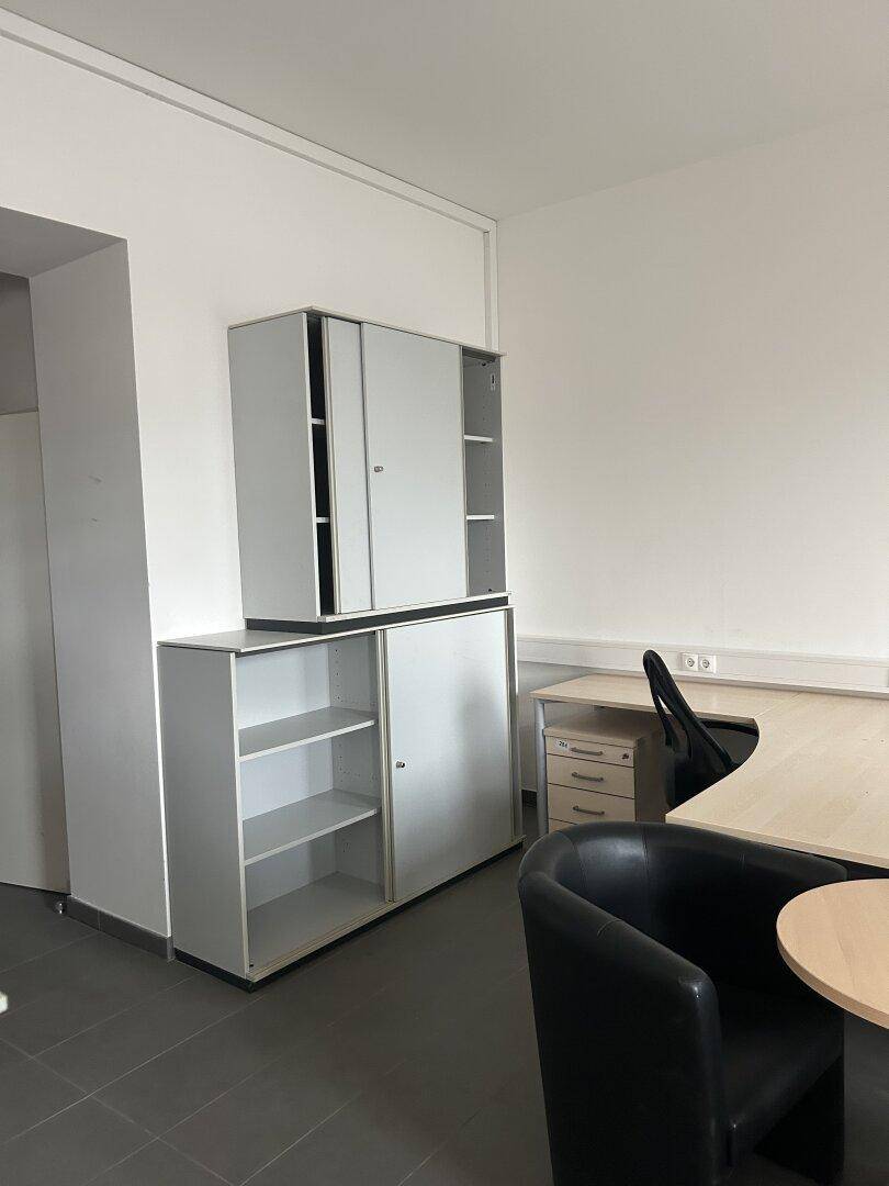 Bürobereich mit gestapelten Schränken, einem Schreibtisch und einem Bürostuhl, funktional eingerichtet.