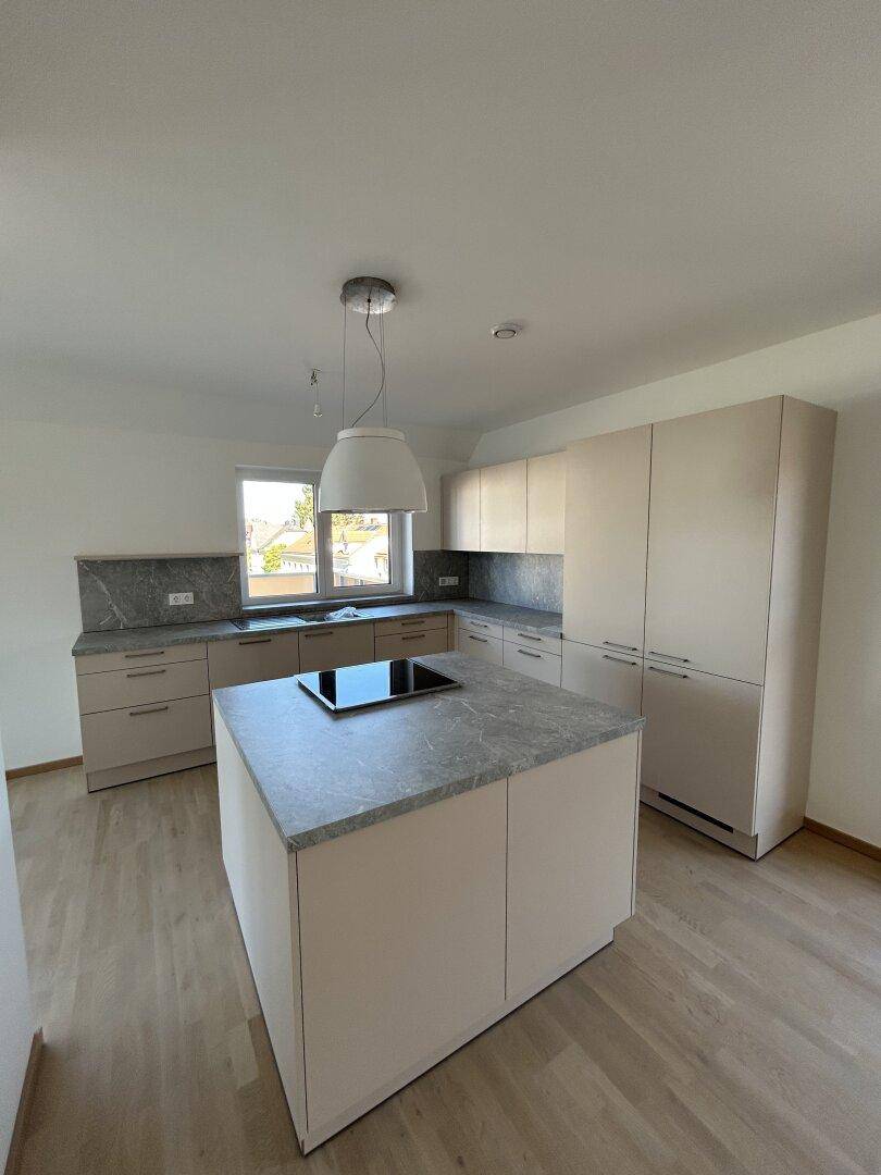 Moderne Einbauküche mit Kücheninsel, Induktionskochfeld und hellen Schränken.