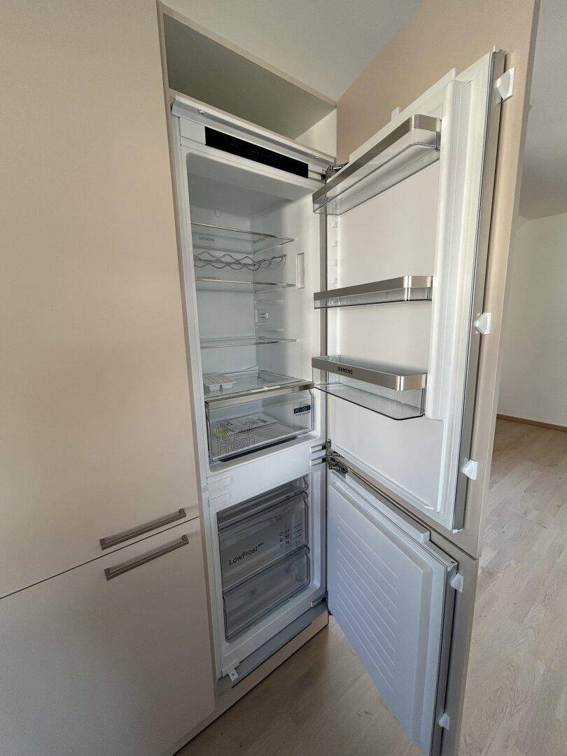 Integrierter Kühlschrank mit Gefrierfach in einer modernen Einbauküche.