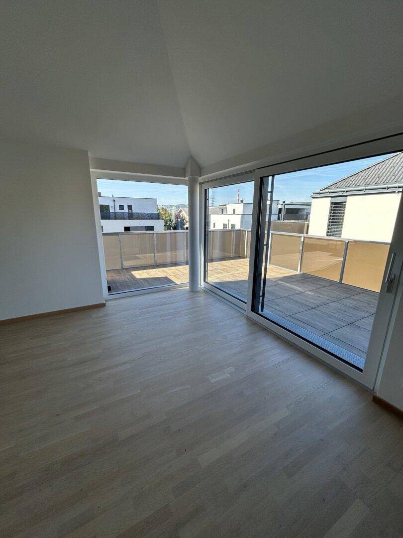 Helles Wohnzimmer mit Holzparkett und großen Schiebetüren zur Dachterrasse.