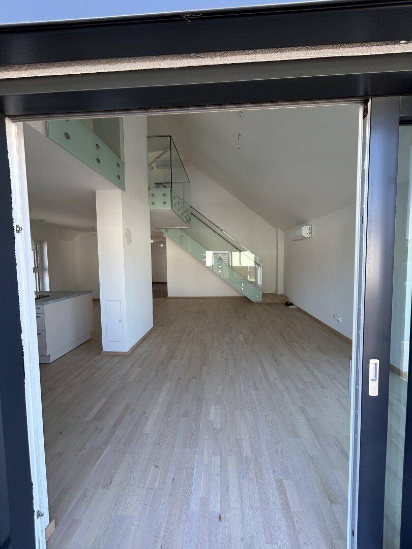 Geräumiger, offener Wohnbereich mit Parkettboden und Zugang zu einem weiteren Raum oder Balkon.