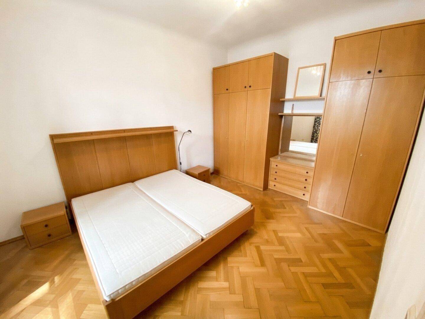 Schlafzimmer mit Doppelbett, passenden Holzschränken und Nachttischen, ausgestattet mit Parkettboden.