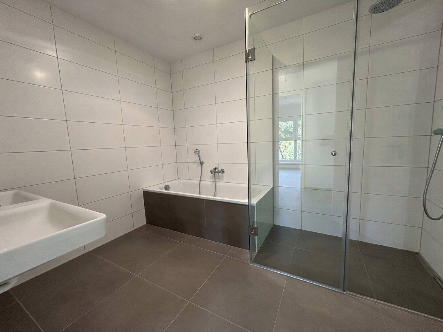 Modernes Badezimmer mit Badewanne, ebenerdiger Dusche und weißen Wandfliesen.