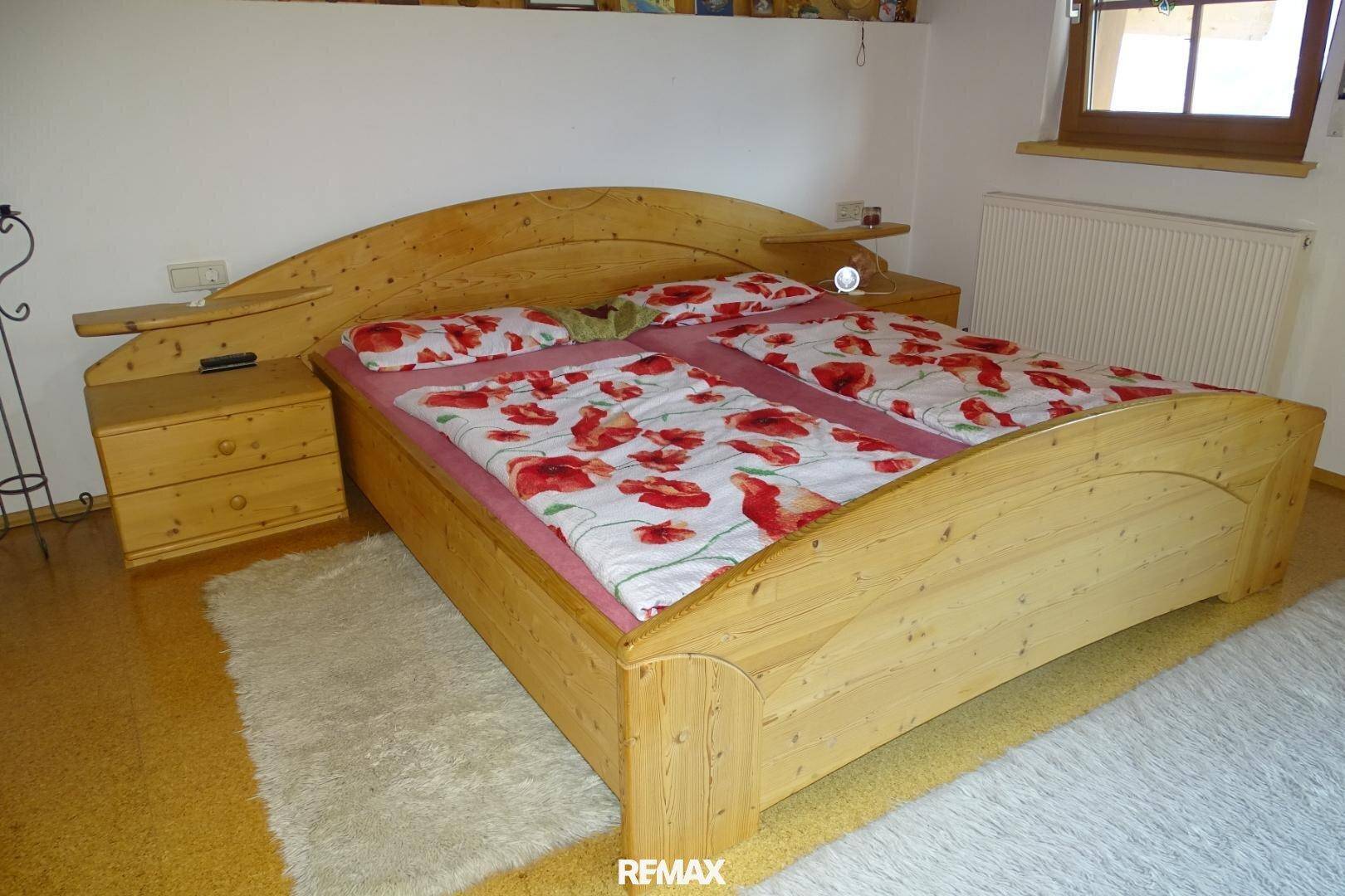 Gemütliches Schlafzimmer mit Doppelbett aus hellem Holz und floraler Bettwäsche.