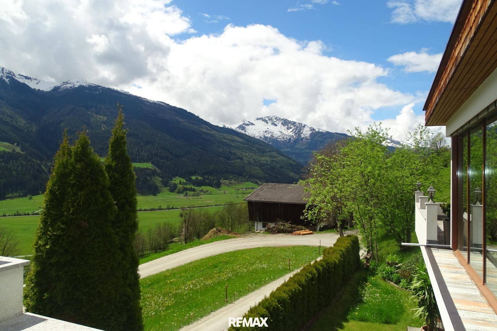 Weitläufige Zufahrt zum Haus mit Blick auf die Berge und die grüne Umgebung.