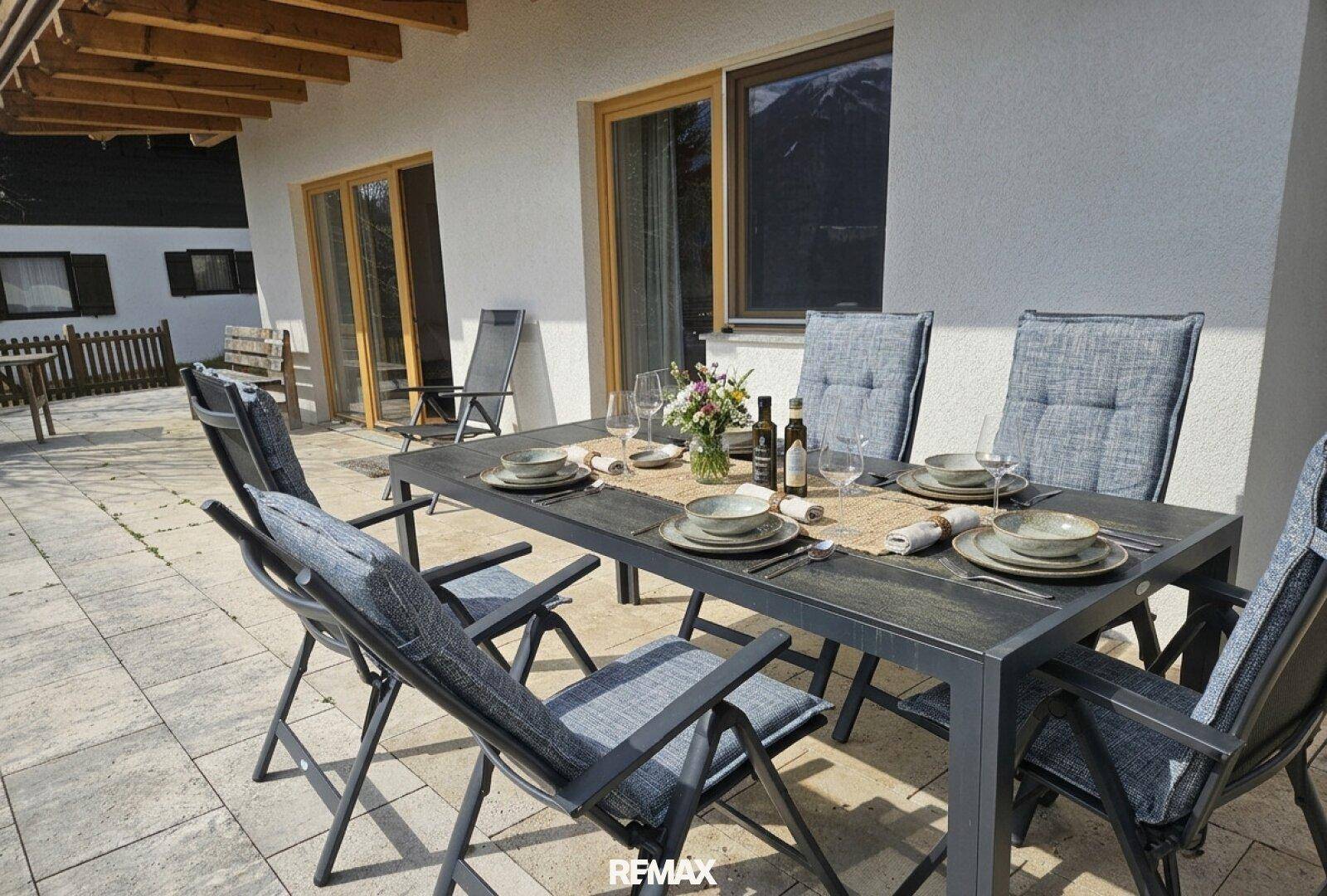 Sonniger Terrassenbereich mit Esstisch und Stühlen für Mahlzeiten im Freien.