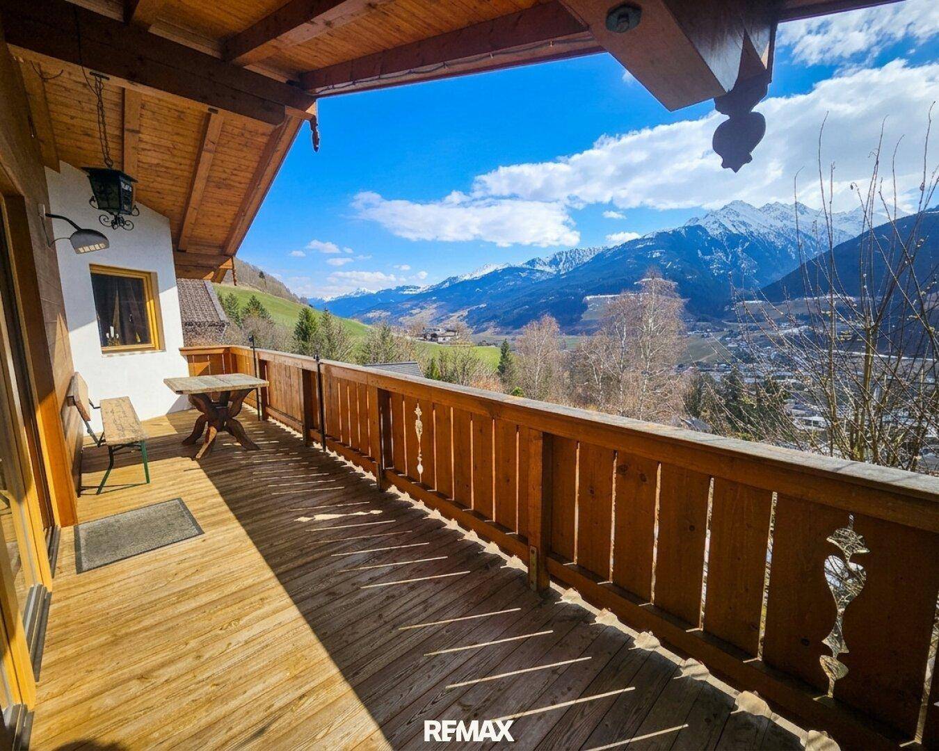 Großer Holzbalkon mit Sitzgelegenheiten und atemberaubendem Bergblick.