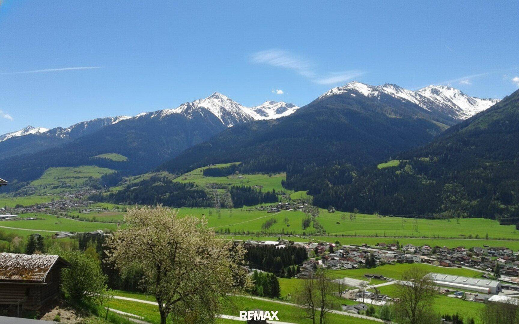 Panoramablick auf die majestätischen Berge und das grüne Tal mit kleinen Ortschaften.