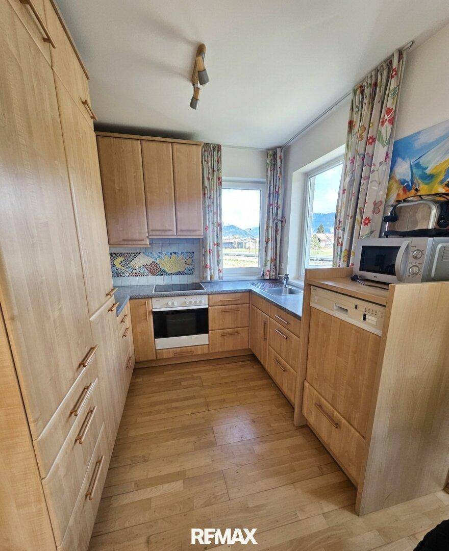 Helle Küche mit Holzschränken, integrierten Geräten und einem Fenster mit Ausblick.