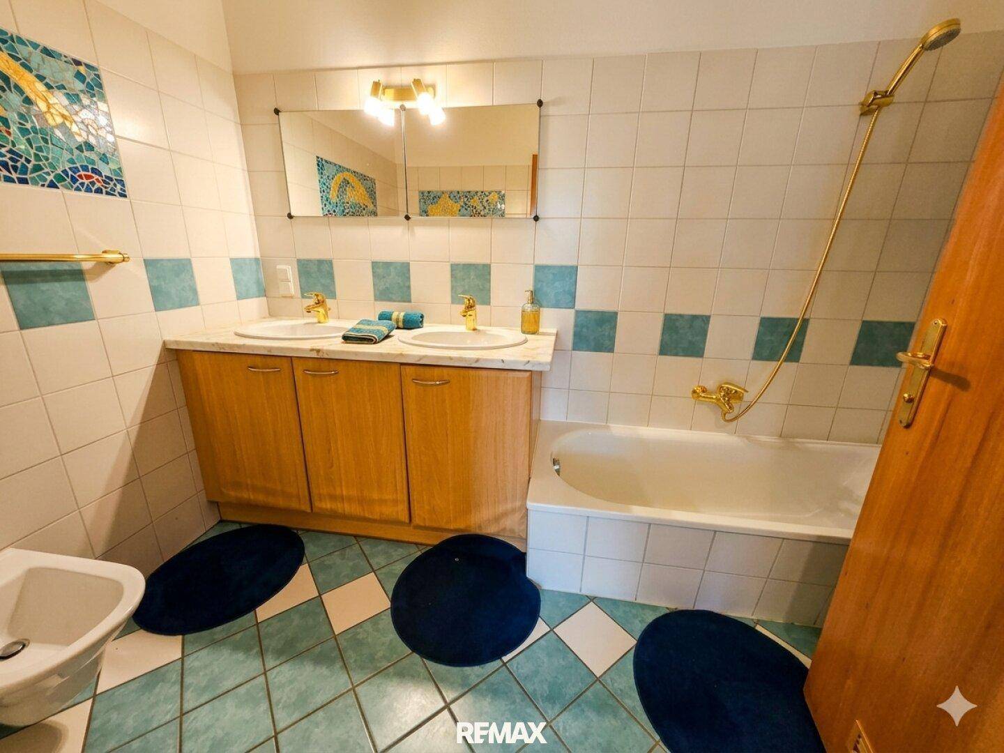 Badezimmer mit blauen und weißen Fliesen, Doppelwaschbecken, Badewanne und Bidet.