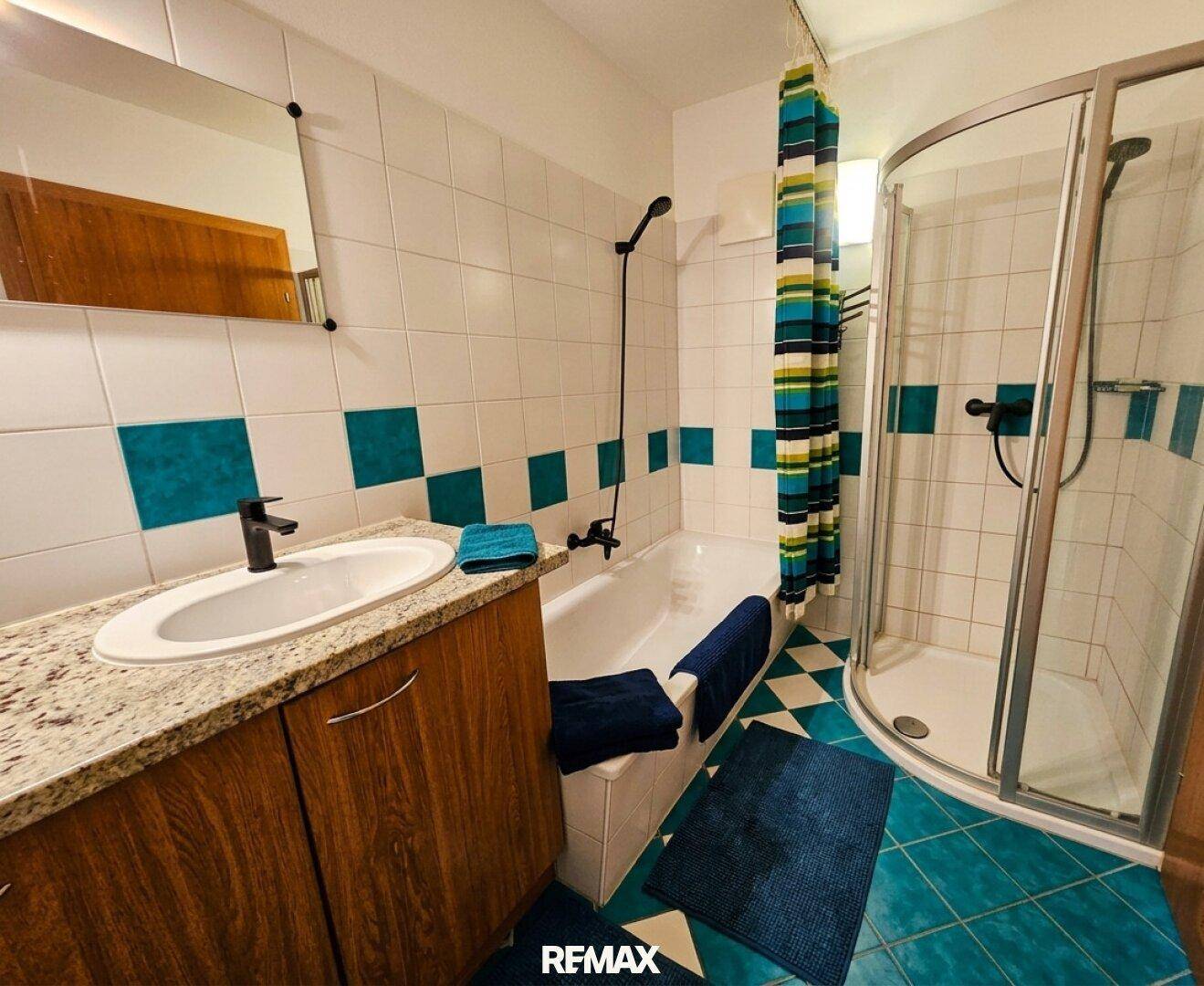 Badezimmer mit blauen und weißen Fliesen, Einzelwaschbecken, Badewanne und Duschkabine.
