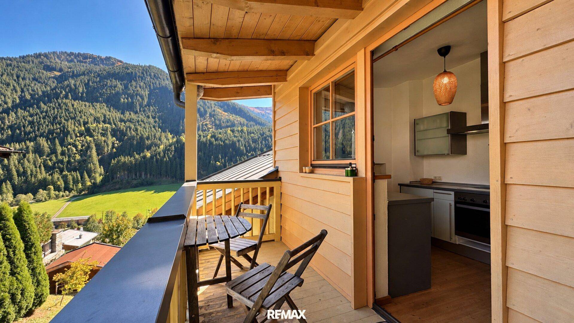 Sonniger Balkon mit Sitzgelegenheiten und atemberaubendem Blick auf die umliegende Berglandschaft.