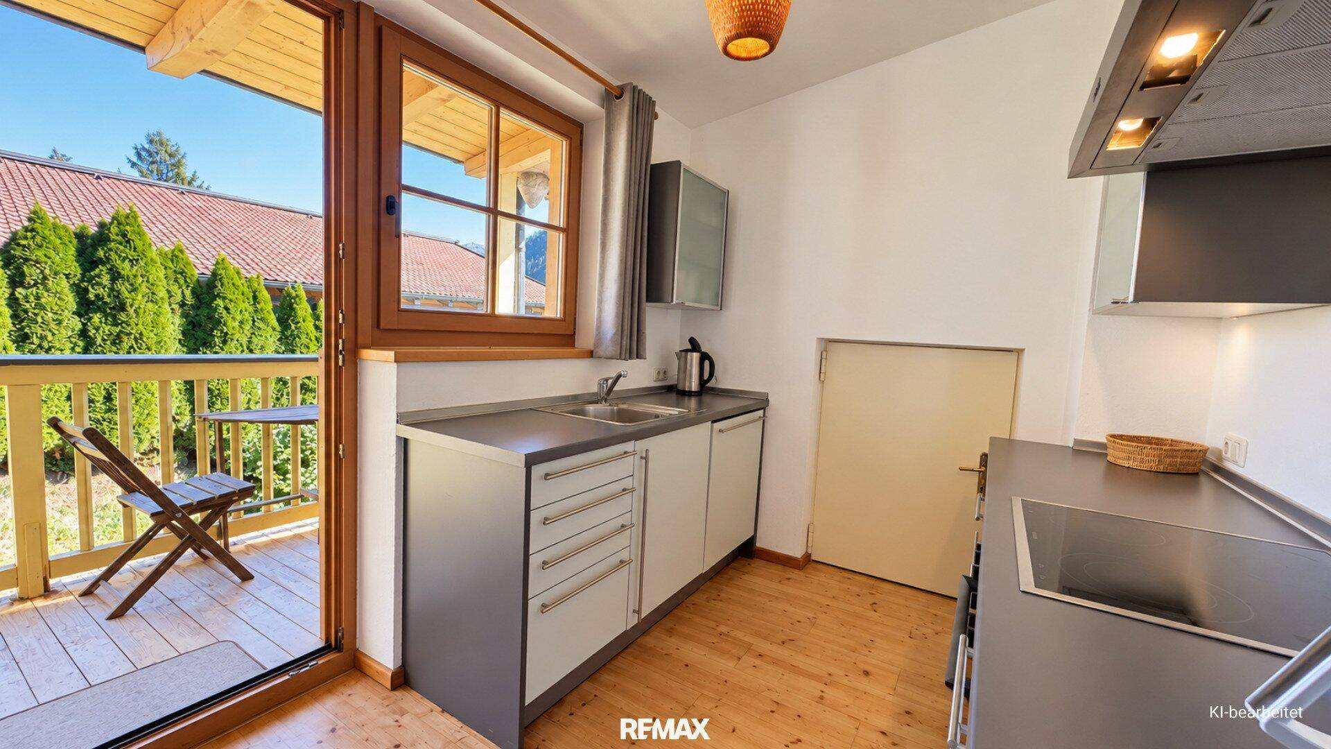 Helle Küchenzeile mit Spülbecken und direktem Zugang zu einem kleinen Balkon.