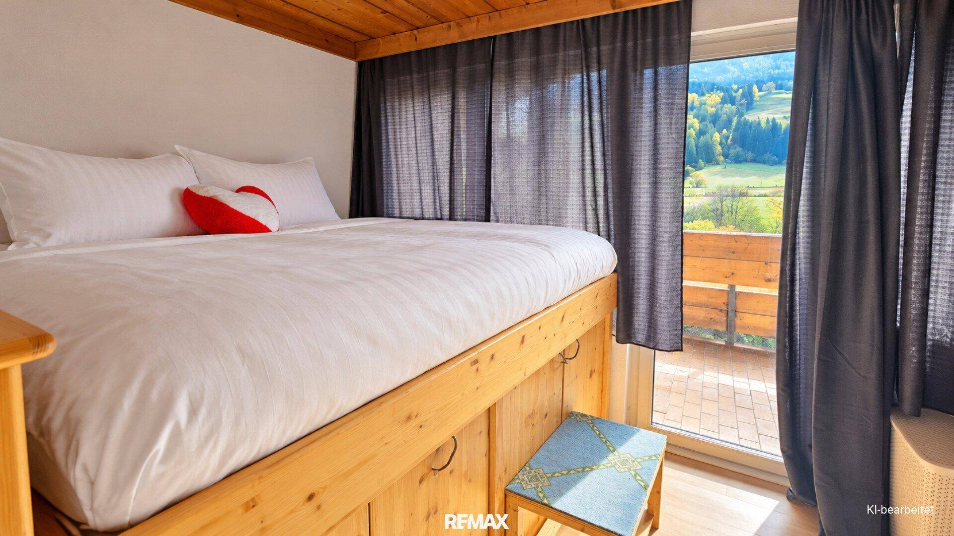 Gemütliches Schlafzimmer mit Holzbett, Holzbalkendecke und direktem Zugang zum Balkon mit Aussicht.