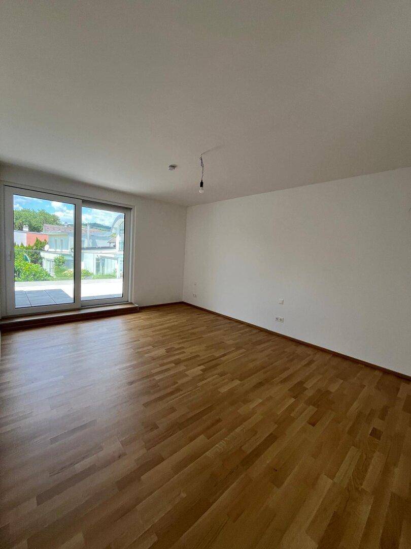 Heller Raum mit Parkettboden und großer Schiebetür, die viel Tageslicht hereinlässt.
