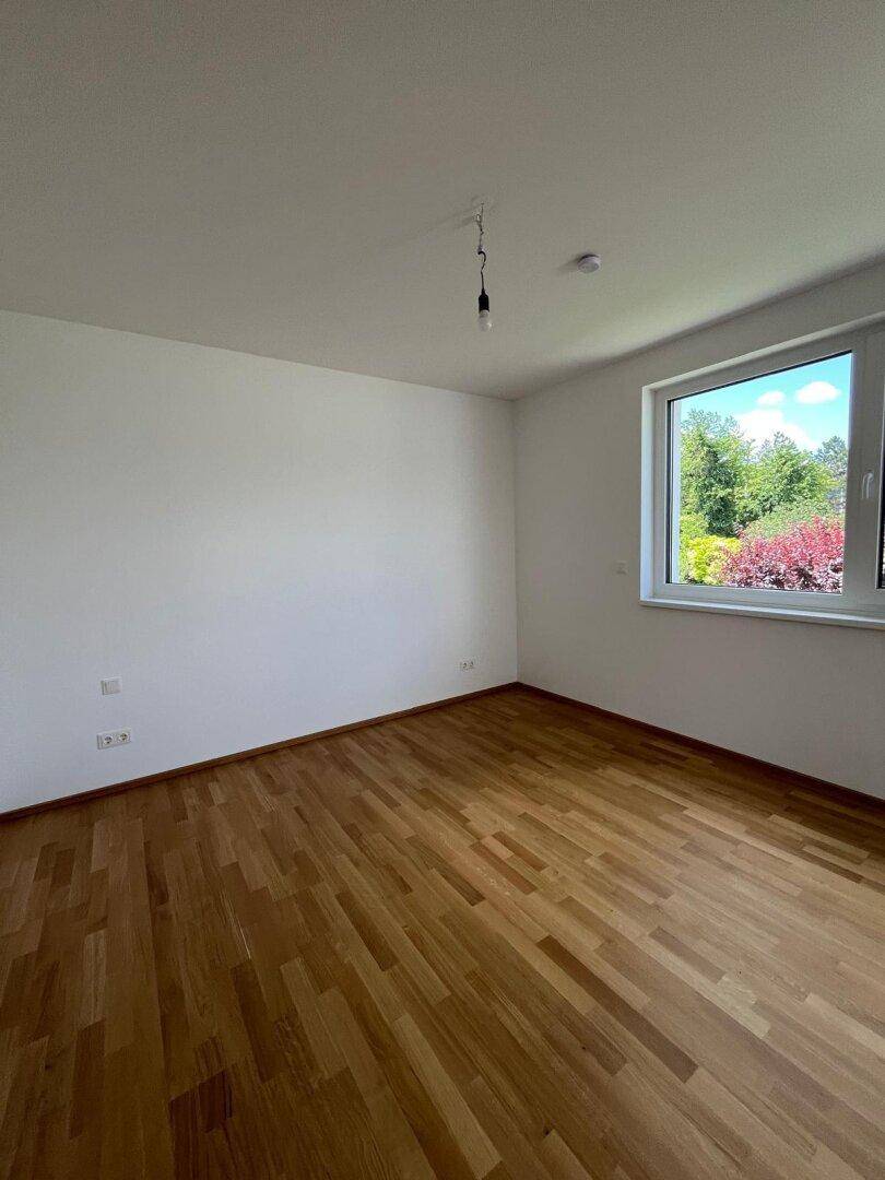 Geräumiges Schlafzimmer mit Parkettboden und Fenster, ideal für individuelle Gestaltung.