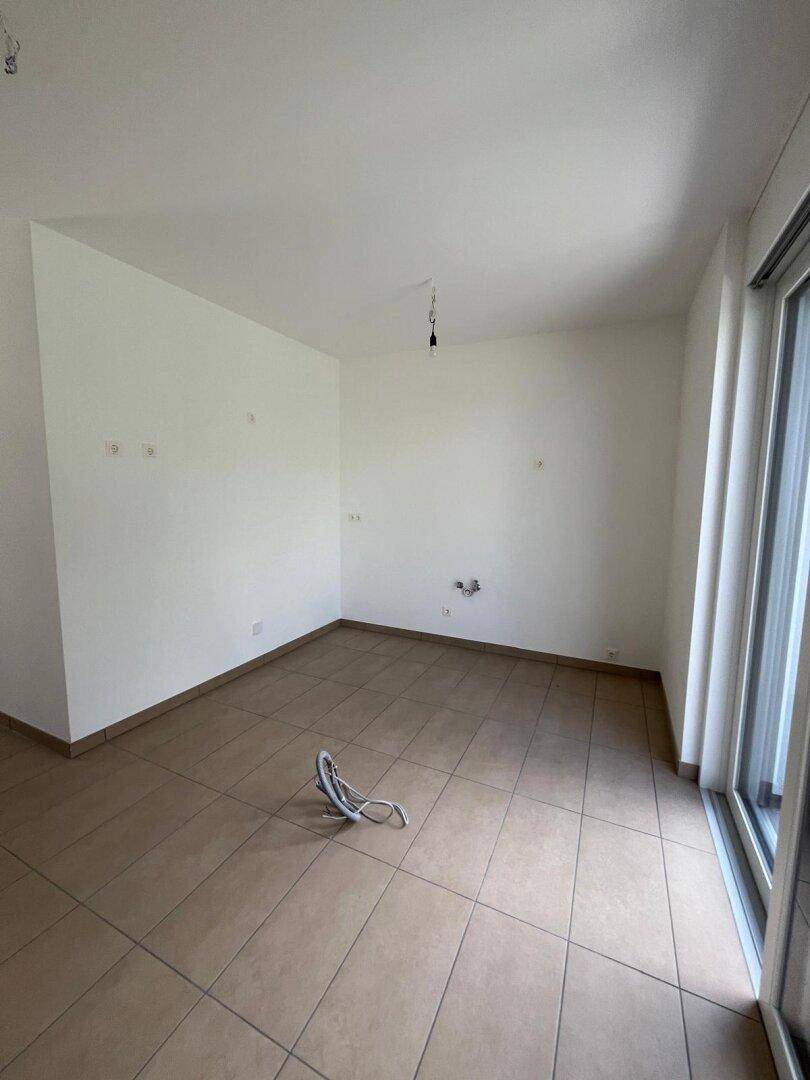 Heller Raum mit Fliesenboden und großen Fenstern, ideal für eine offene Küche.