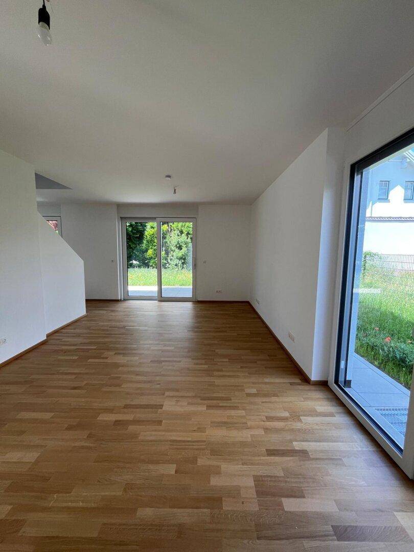 Heller Wohnbereich mit Parkettboden und großen Schiebetüren, die viel Tageslicht hereinlassen.