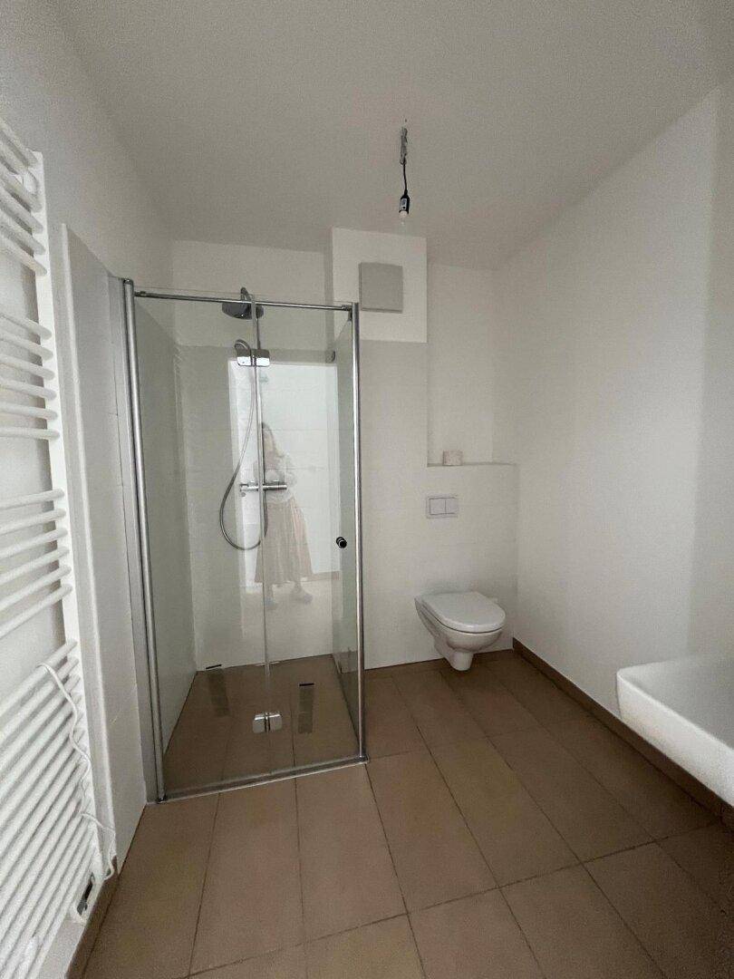 Modernes Badezimmer mit ebenerdiger Dusche, Waschbecken und beheiztem Handtuchhalter.