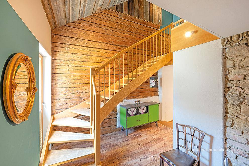 Rustikale Holztreppe mit offenem Design und einer Wand aus Altholz, die zu den oberen Etagen führt.