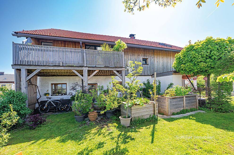 Rückseite des Hauses mit einem gepflegten Garten, Hochbeeten und einem Balkon im Obergeschoss.
