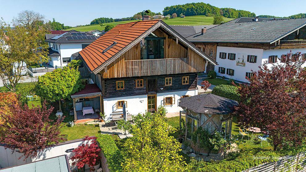 Luftaufnahme des Anwesens mit traditionellem Haus, großem Garten und umliegender Wohnbebauung.