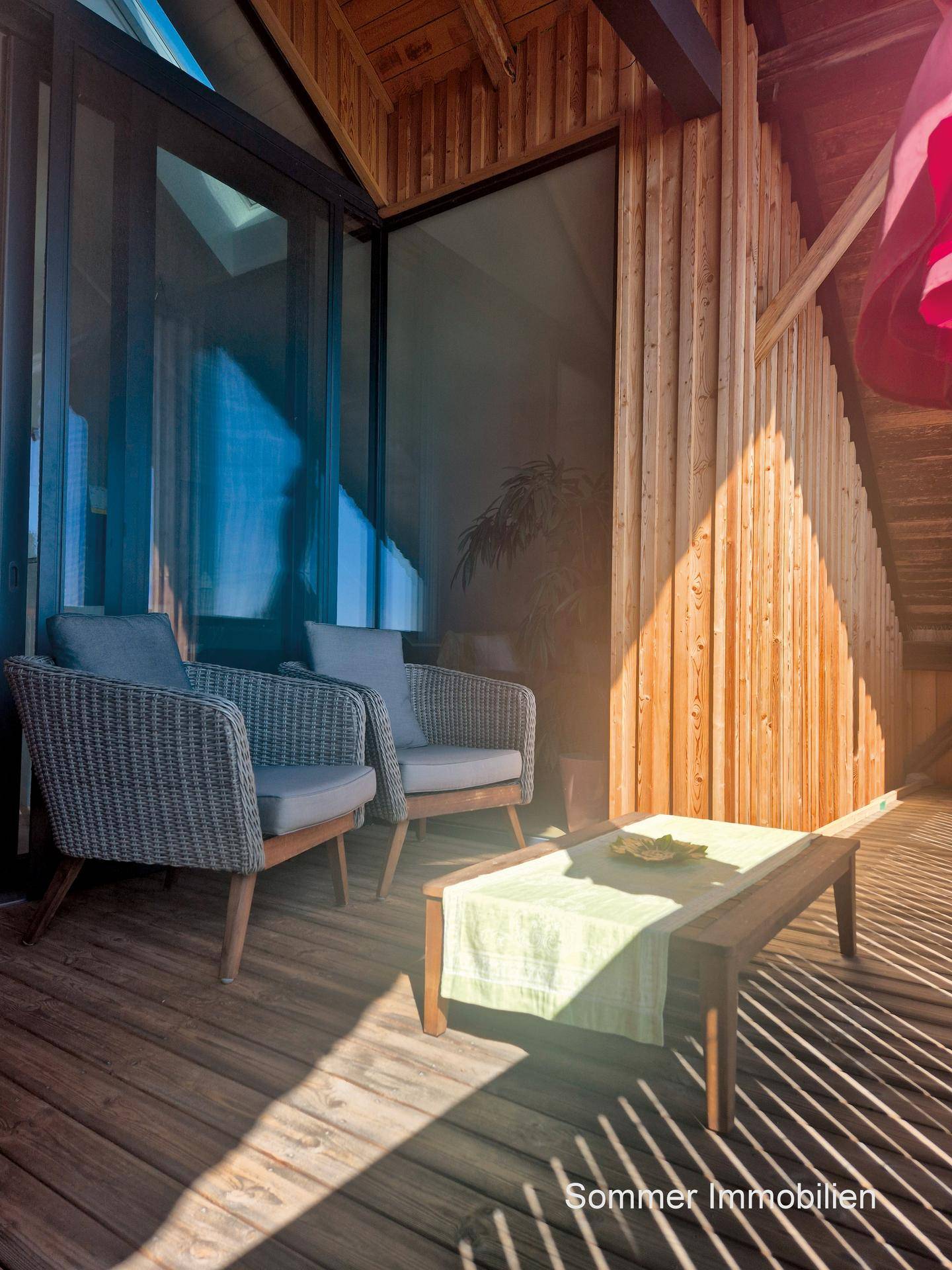 Sonniger Holzbalkon mit bequemen Sitzgelegenheiten und Blick auf die Umgebung, ideal zum Entspannen.