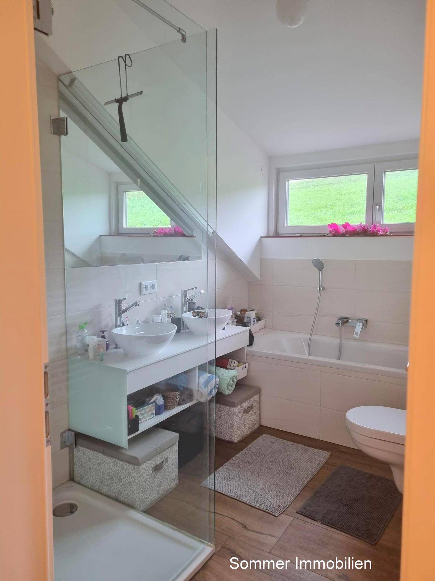 Modernes Badezimmer mit Doppelwaschbecken, Badewanne, Dusche und Fenster unter Dachschräge.