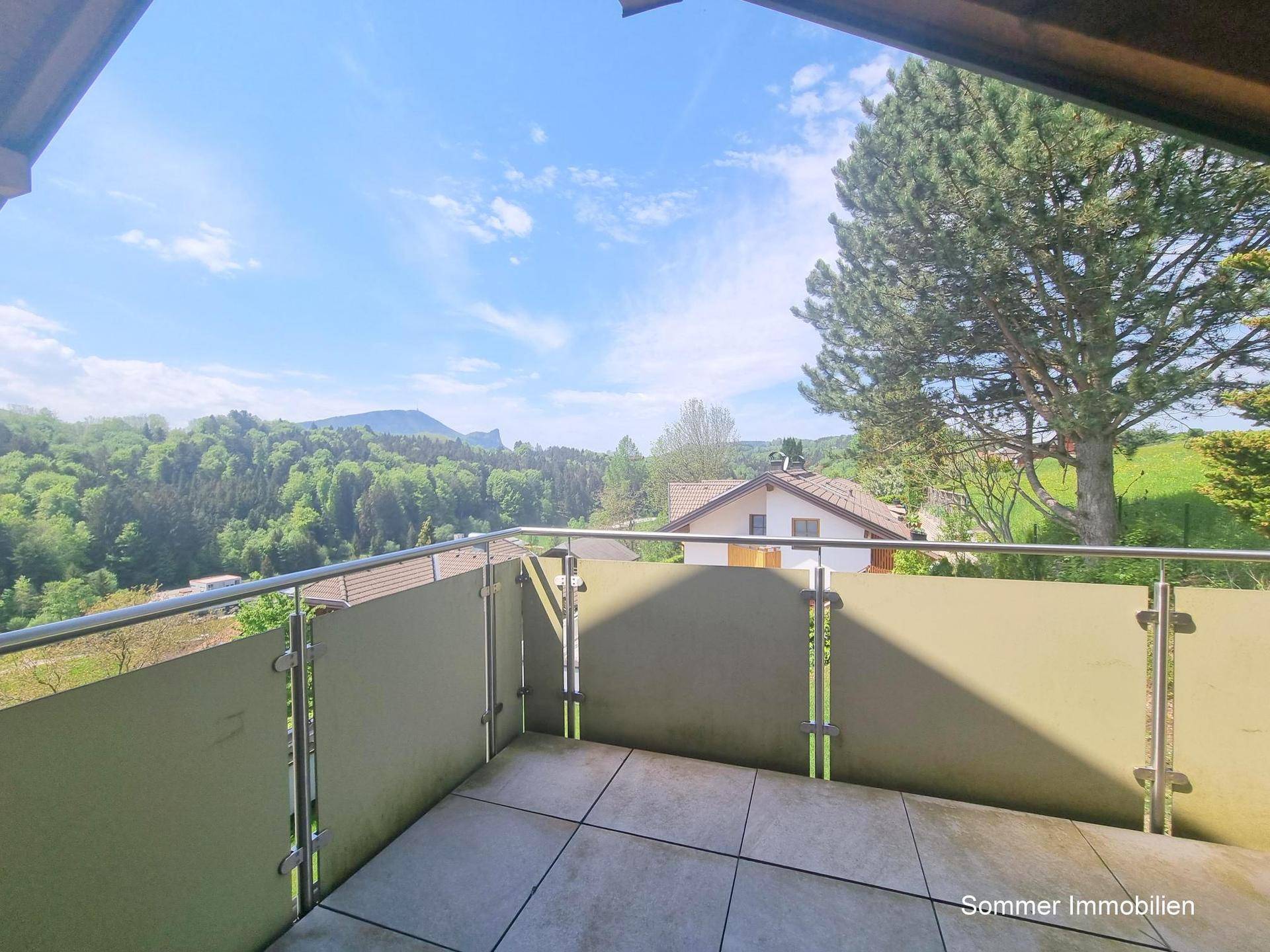 Geräumiger Balkon mit Fliesenboden und weitem Blick auf grüne Hügel und Berge.