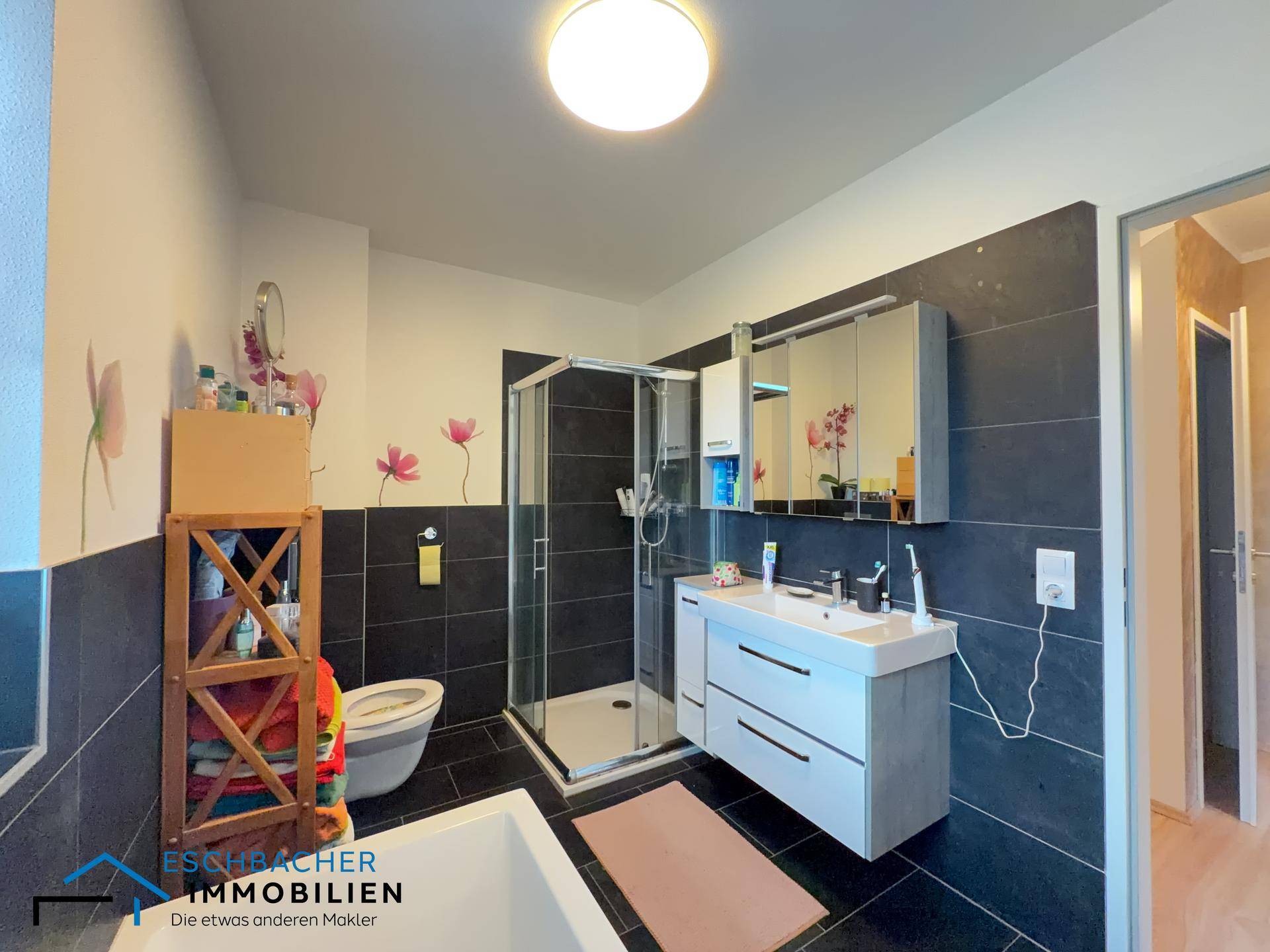 Modernes Badezimmer mit dunklen Fliesen, Dusche, Badewanne und Einzelwaschbecken.