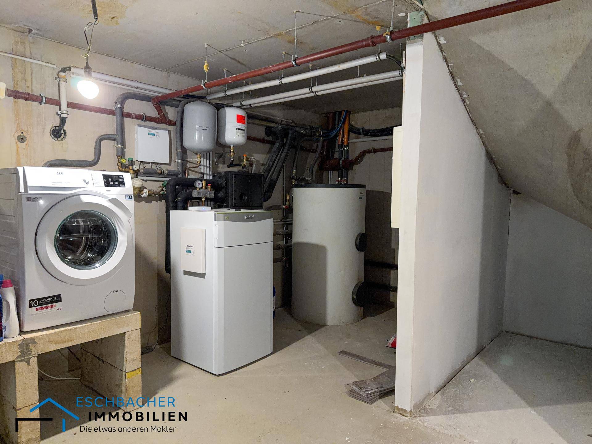 Hauswirtschaftsraum im Keller mit Heizungsanlage, Warmwasserspeichern und Waschmaschine.