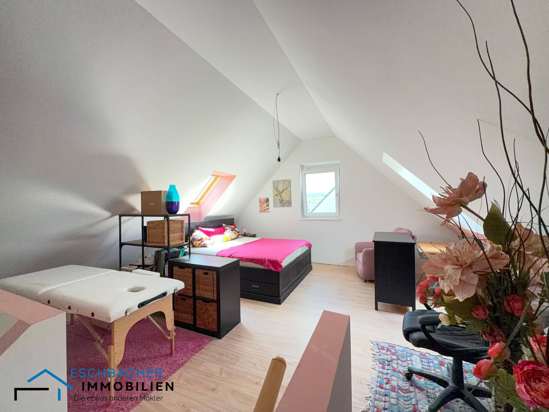 Dachgeschosszimmer mit schrägen Wänden, Holzboden und einem Bett, vielseitig nutzbar.