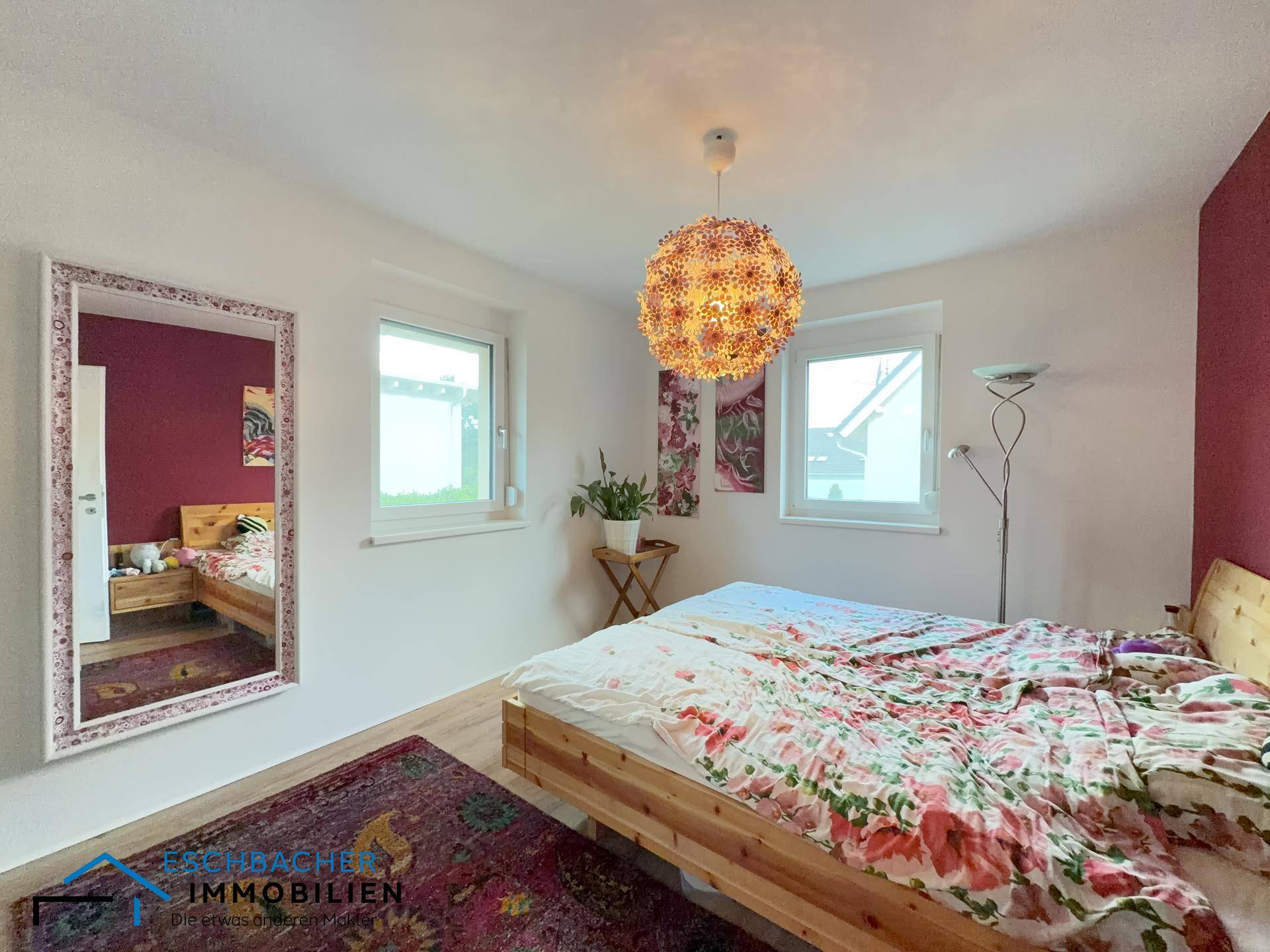 Gemütliches Schlafzimmer mit Doppelbett, farbiger Wand und dekorativer Deckenleuchte.