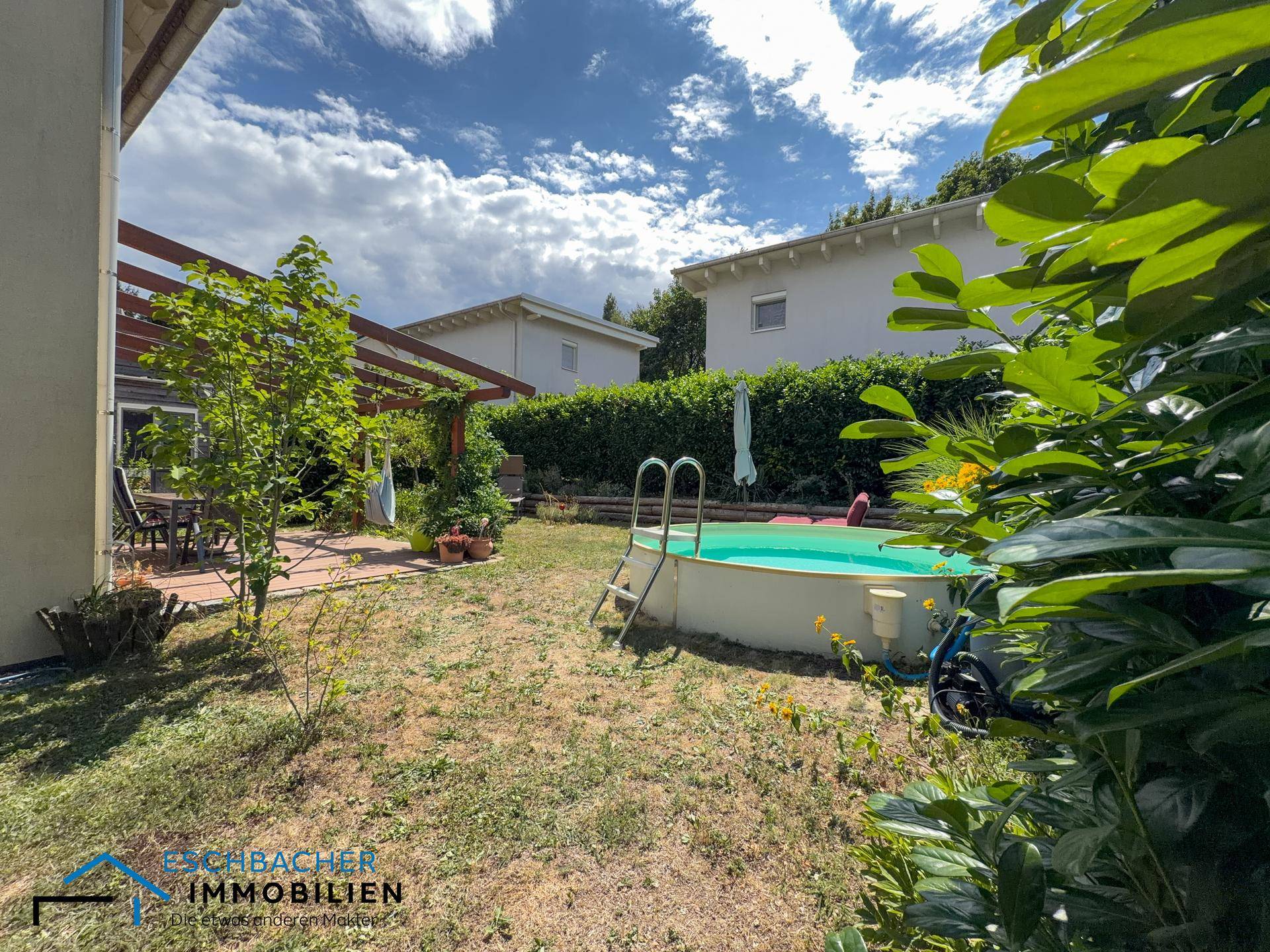 Weitläufiger Garten mit Aufstellpool, umgeben von Bäumen und Sträuchern.