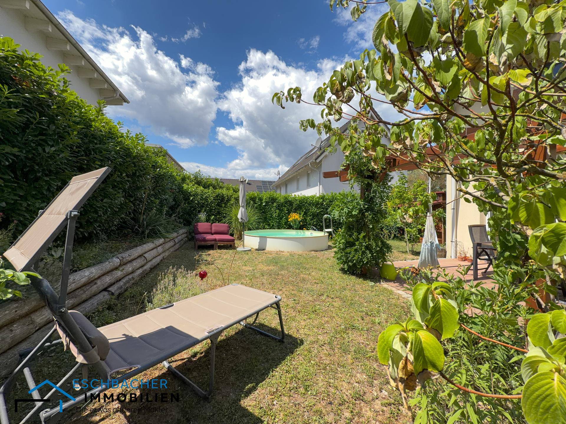 Großer Garten mit Liegestuhl, Aufstellpool und dichter Hecke als Sichtschutz.