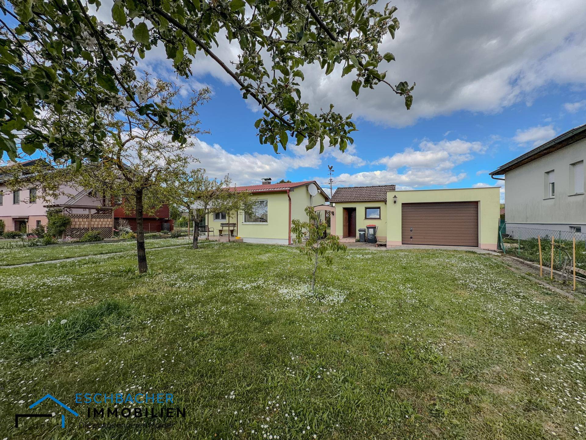 Ansicht des Einfamilienhauses mit angrenzender Garage und großem, gepflegten Gartenbereich.