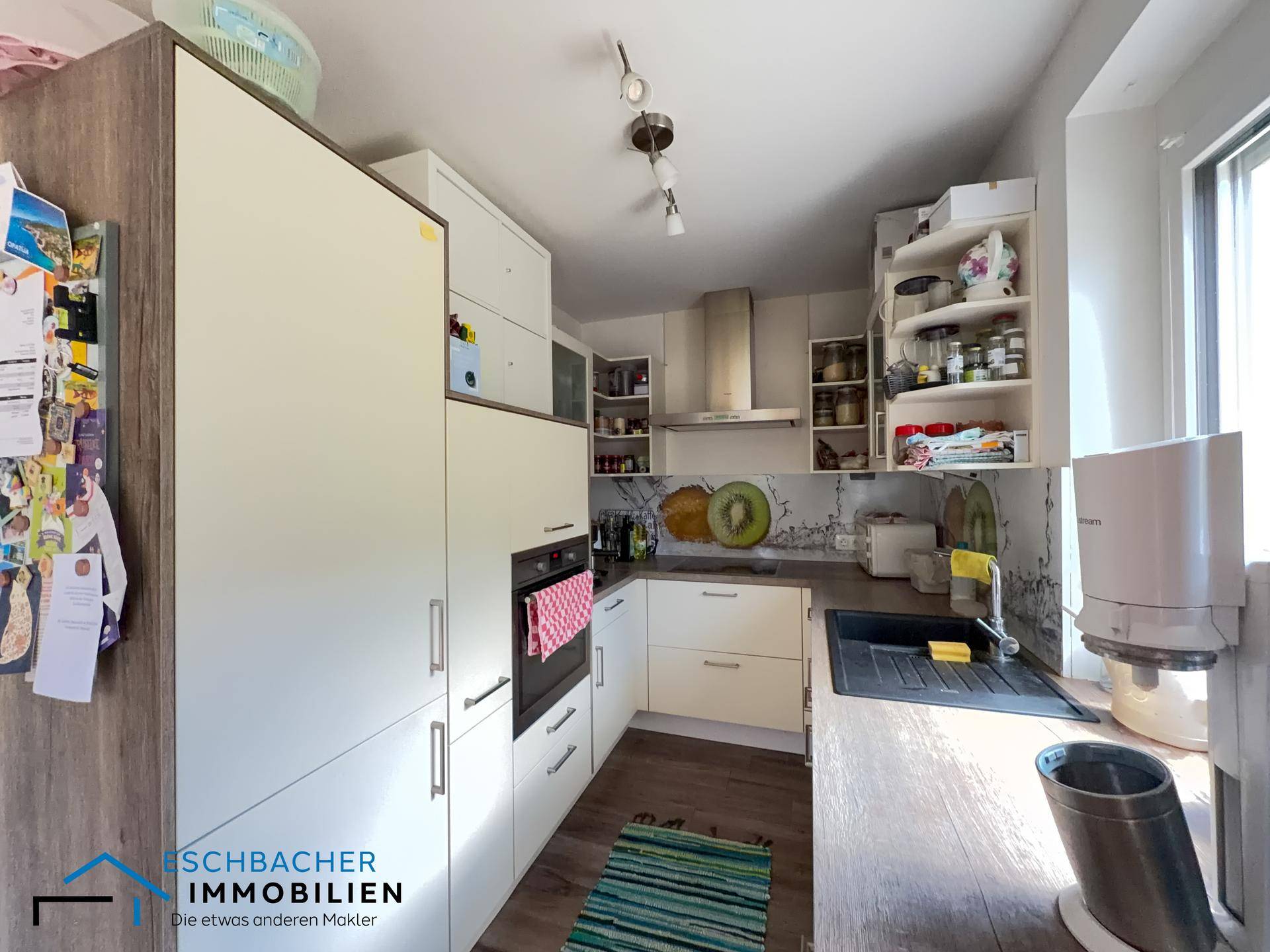Moderne Küche mit hellen Schränken, Holz-Arbeitsplatte und integrierten Geräten.