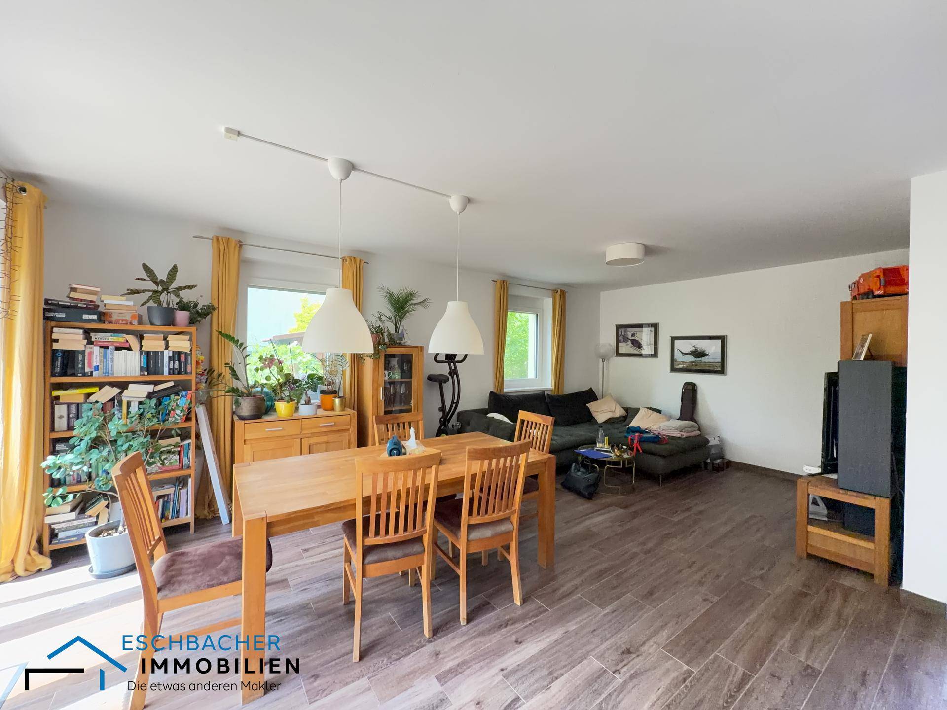 Heller Wohn- und Essbereich mit Holztisch, Bücherregalen und Blick in den Garten.