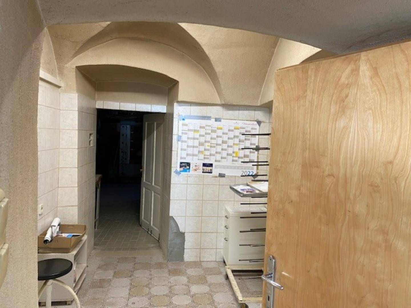 Flur mit charakteristischen Gewölbedecken und Fliesenboden, der zu weiteren Räumen führt, mit einem Kalender an der Wand.