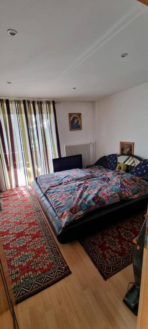 Gemütliches Schlafzimmer mit Doppelbett, Holzboden und farbenfrohen Teppichen.