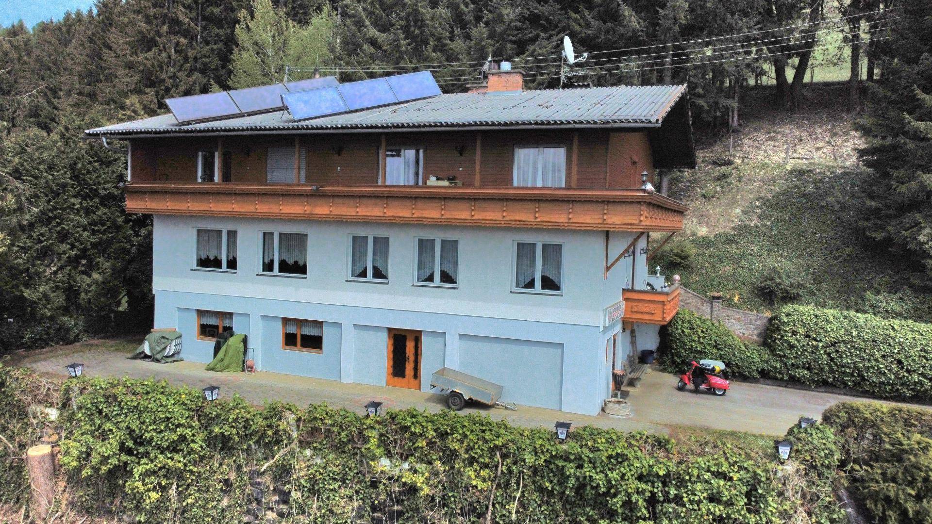 Mehrstöckiges Gebäude mit Balkonen, Solaranlage auf dem Dach und Garage.