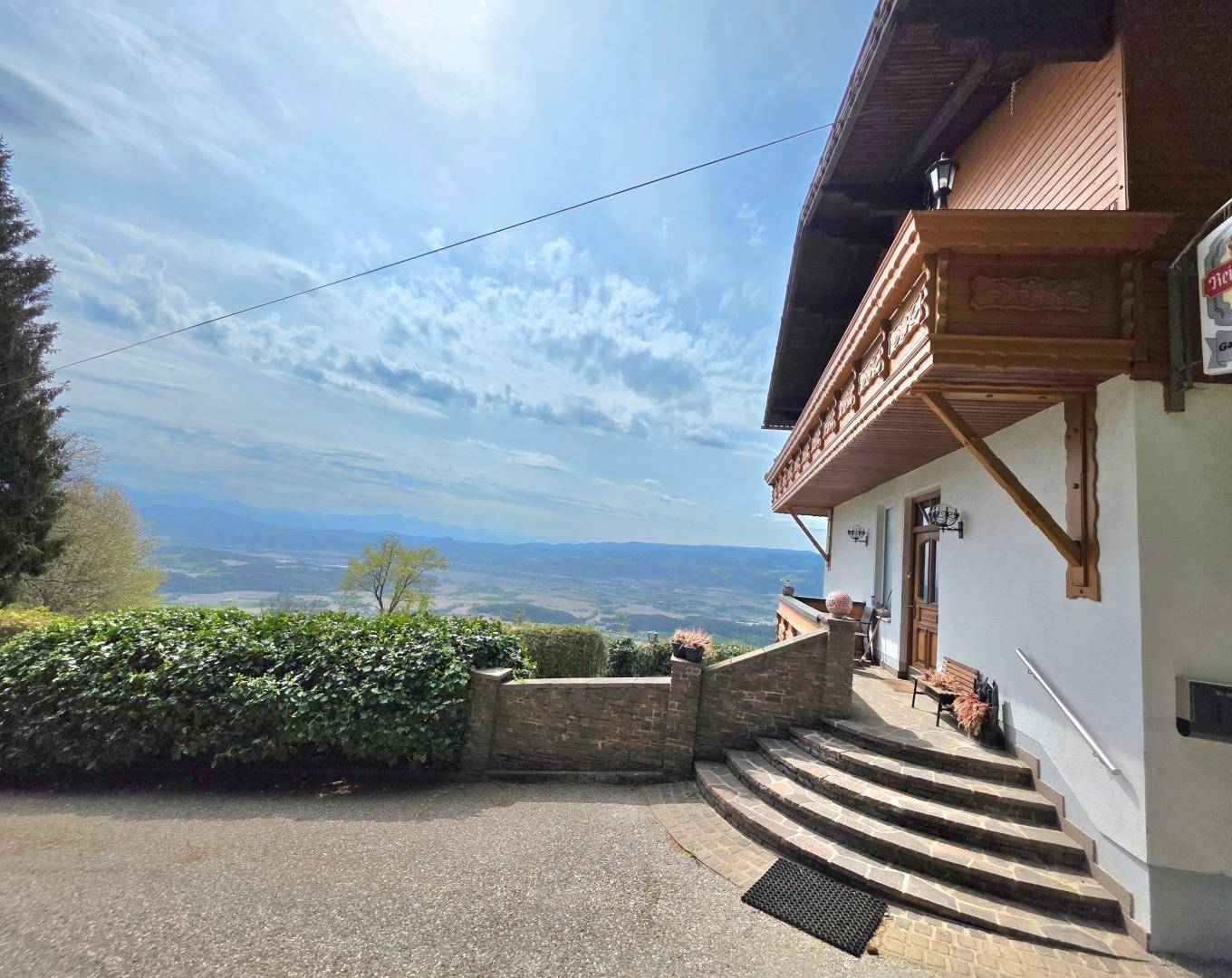 Traditionelles Gebäude mit Holzbalkonen und weitem Panoramablick über das Tal.