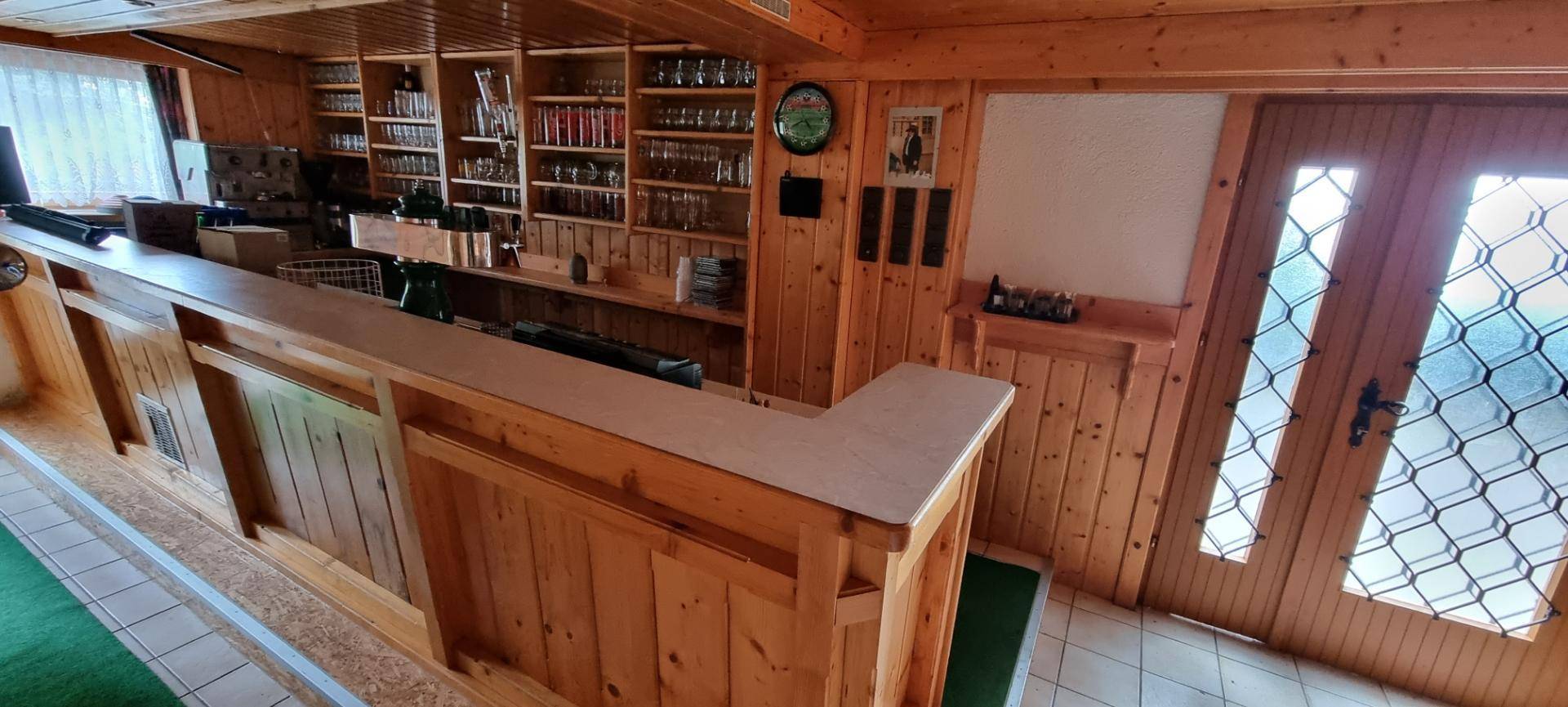 Rustikale Bar mit Holztäfelung und Regalen für Getränke und Gläser.