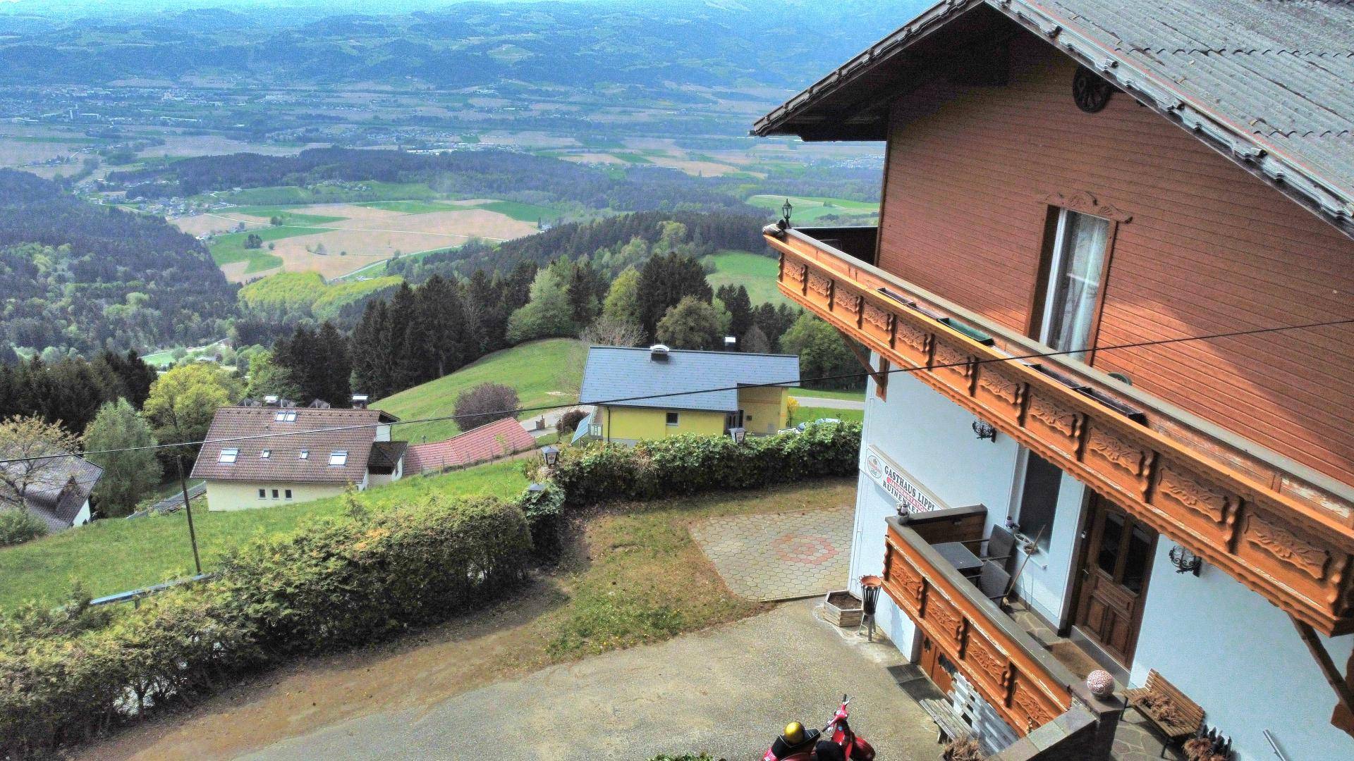 Gebäude in alpiner Architektur mit Holzbalkonen und weitem Blick über das grüne Tal.